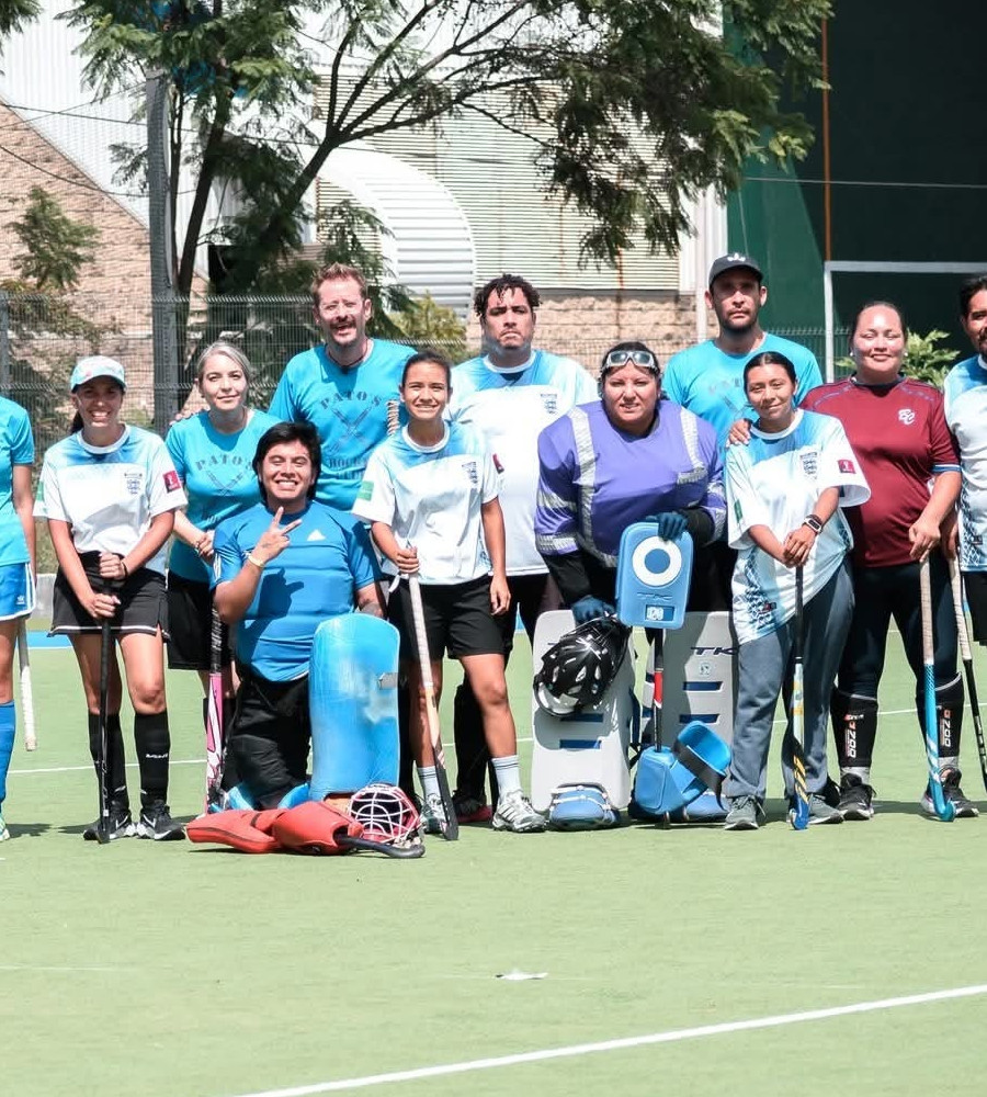 Adultos jugando hockey recreativo en césped sintético al atardecer